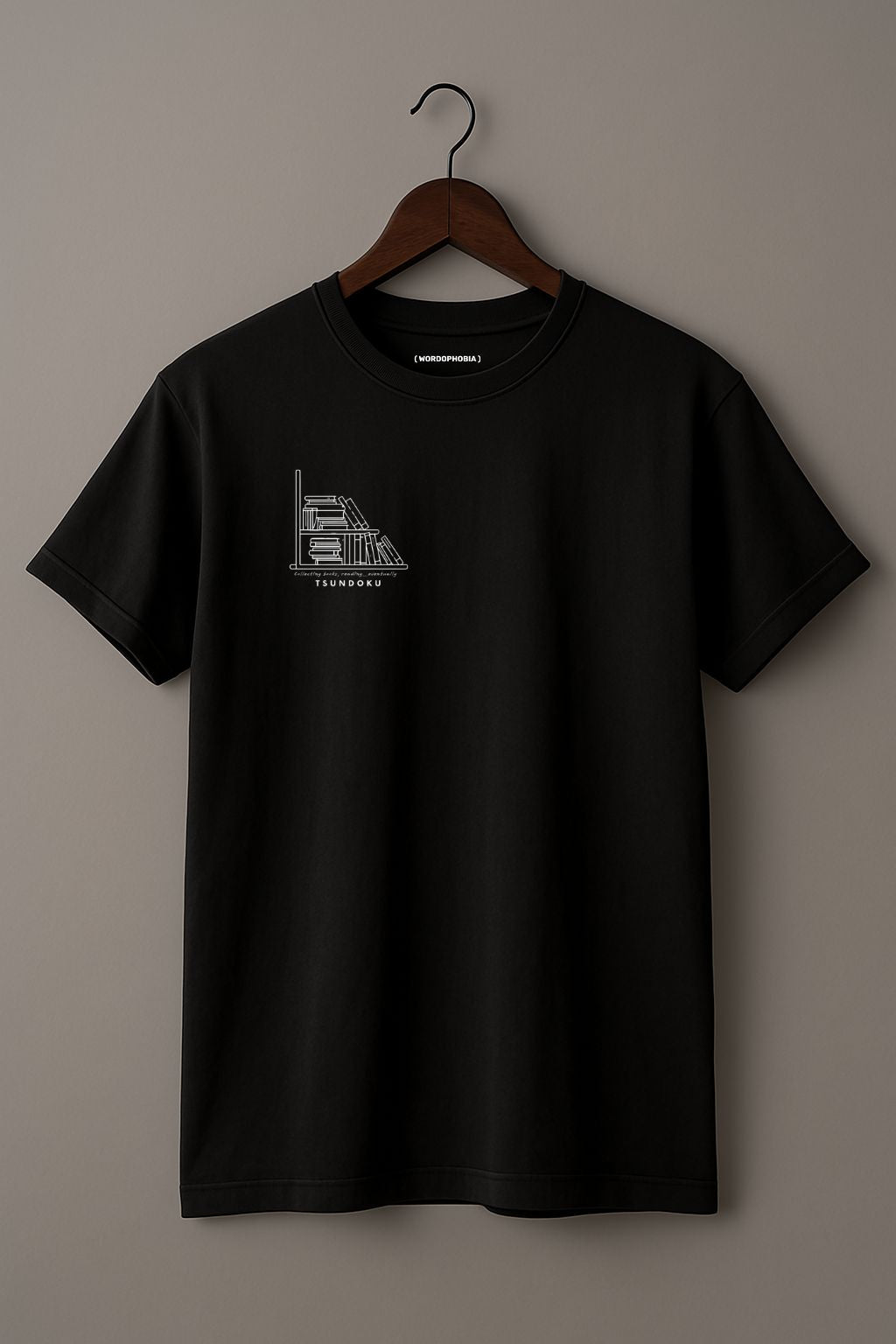 Mockup of minimalist unisex folded t-shirt with the word “Tsundoku” in black cotton