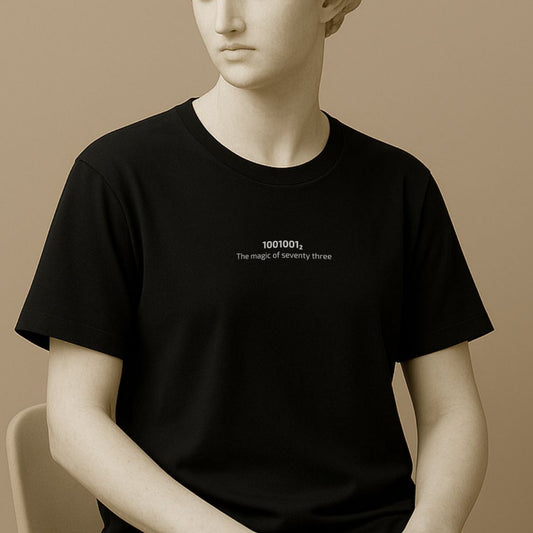 Statue wearing a black t-shirt with white Binary code '1001001_2' displayed on a black background with text 'The magic of seventy three' on a beige background