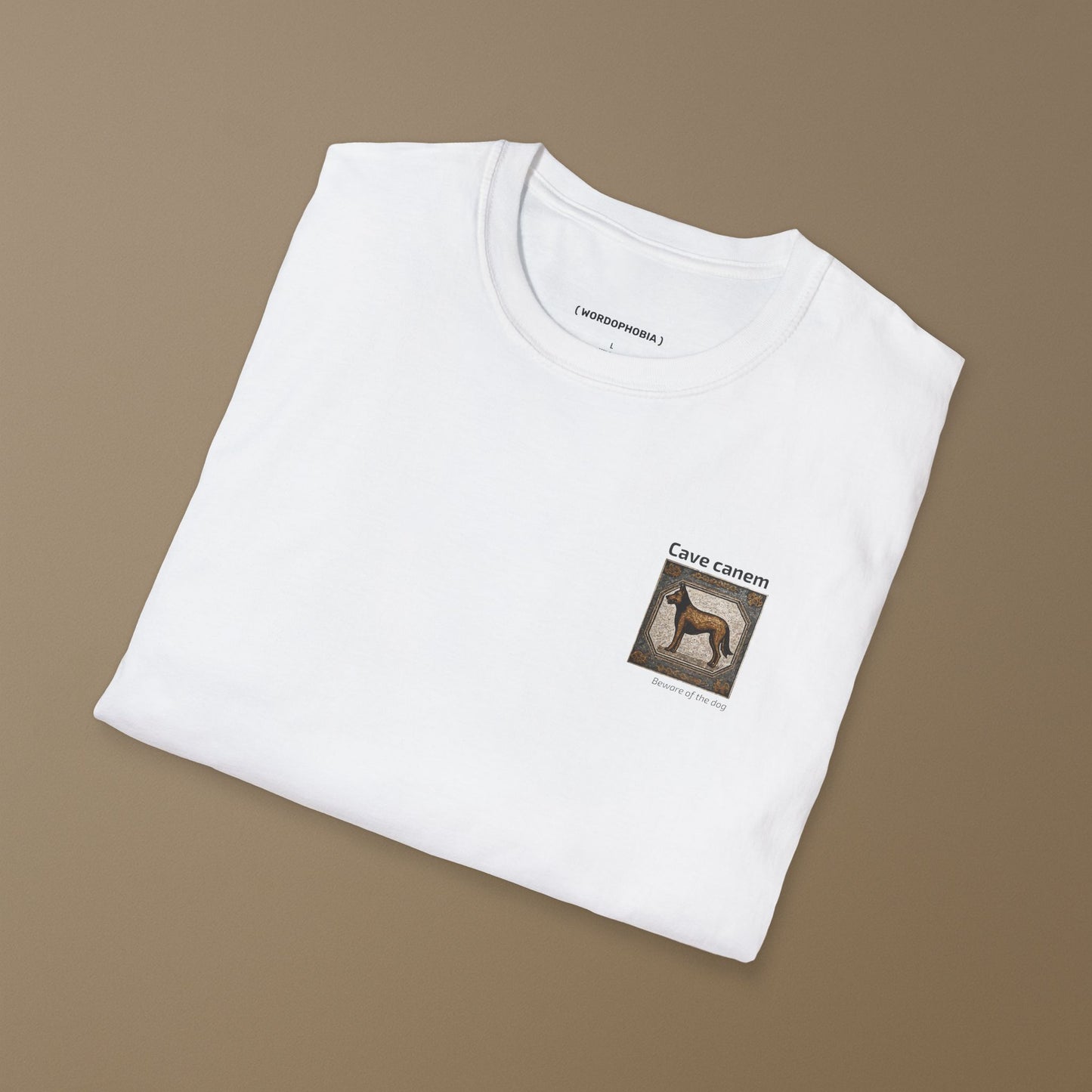 Folded white t-shirt with a small graphic of a tile with a dog illustration and 'Cave canem' (Beware of the dog) text on a beige background