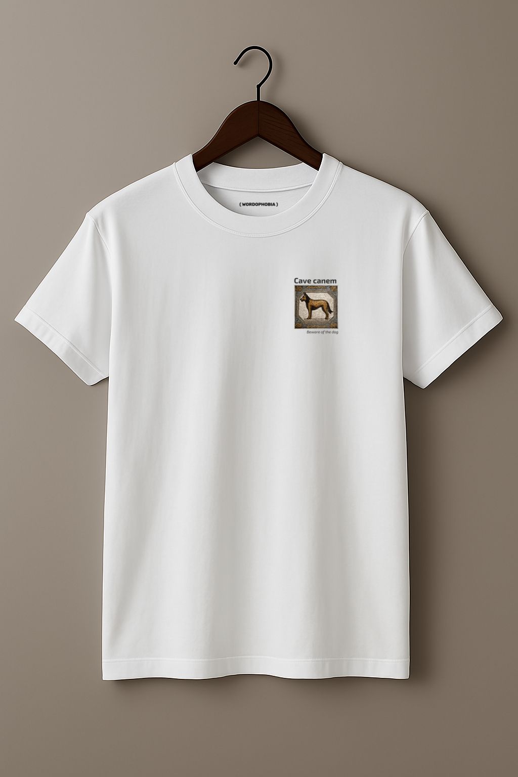 White t-shirt with a small graphic of a tile with a dog illustration and 'Cave canem' (Beware of the dog) text on a hanger against a plain background