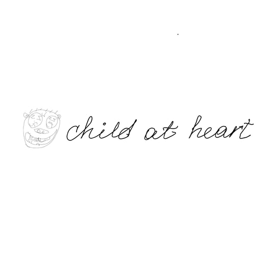 Black hand drawn kids picture of the funny face and the hand written text "child at heart" on a white background