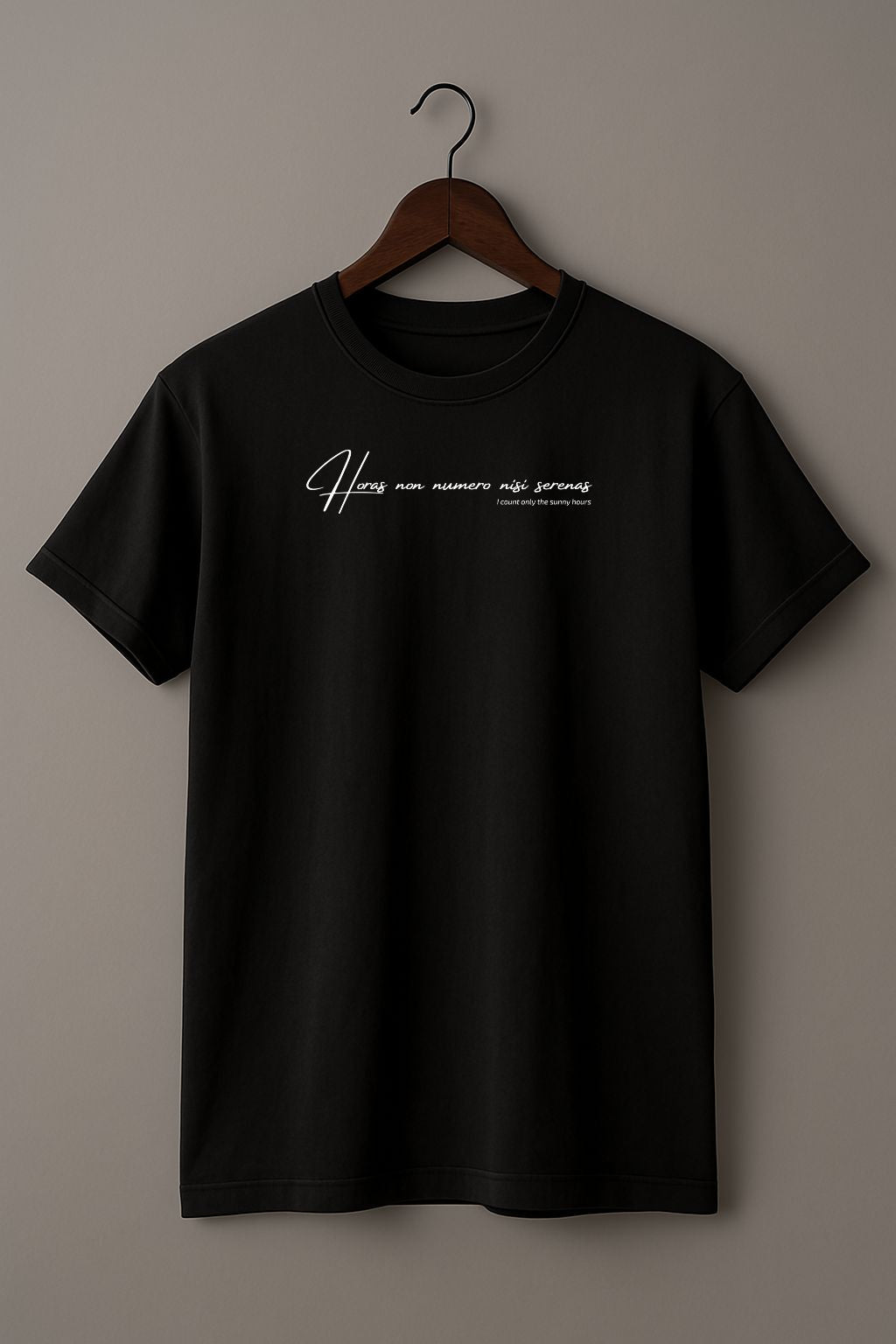 Black t-shirt with white Latin phrase "Horas non numero nisi serenas" on a wooden hanger against a beige wall
