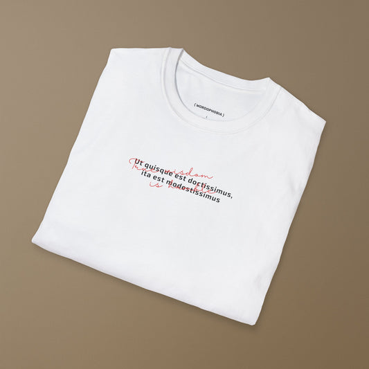 Folded white t-shirt with the Latin phrase “Ut quisque est doctissimus, ita est modestissimus” on a beige background