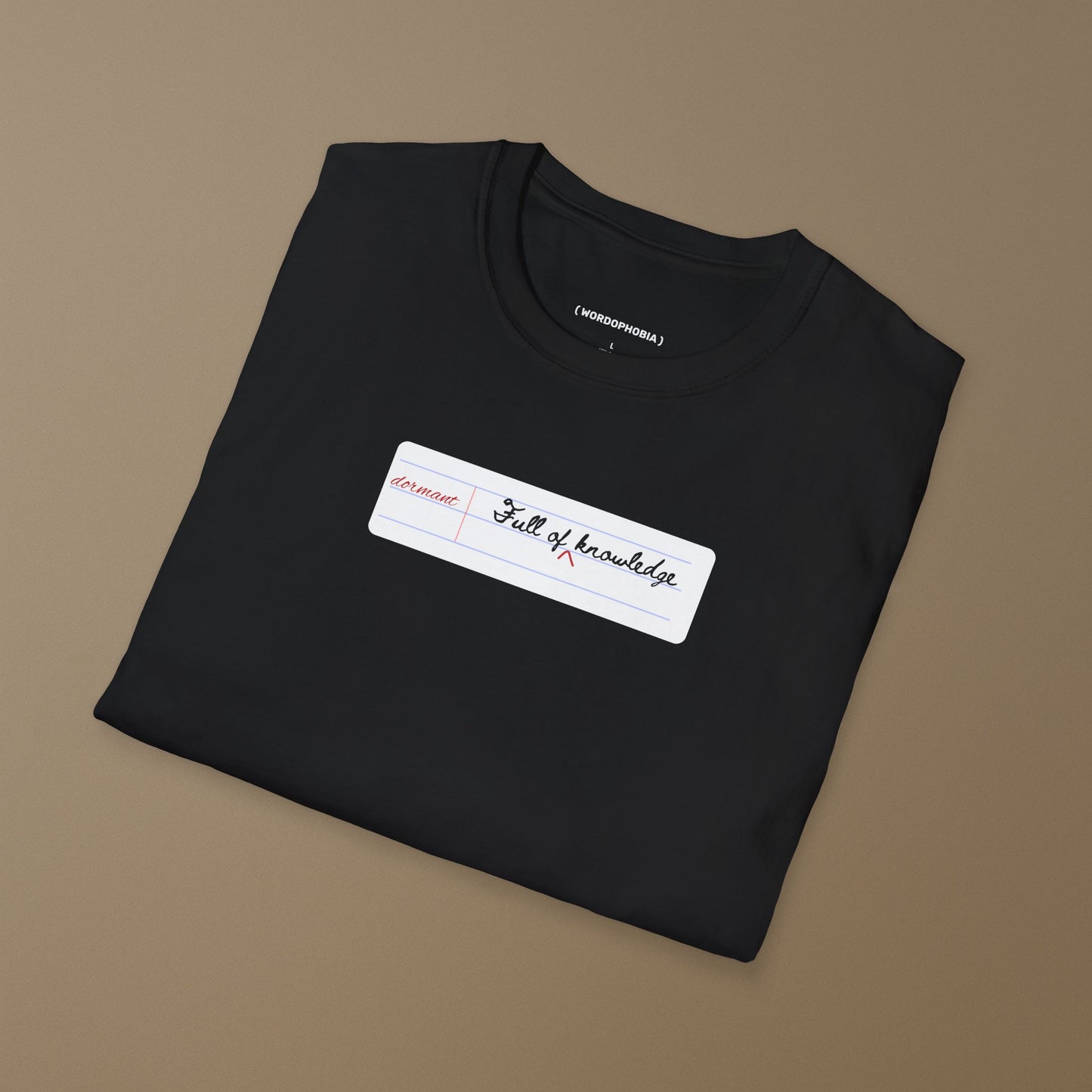 Folded black t-shirt with a white notebook page with 'dormant' and 'Full of knowledge' on a hanger against a beige background