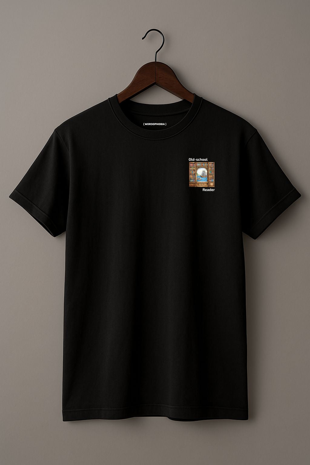 Mock up of black t-shirt with a small graphic and text "Old-school reader" on a wooden hanger on a beige background