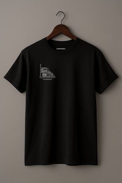 Mockup of minimalist unisex folded t-shirt with the word “Tsundoku” in black cotton