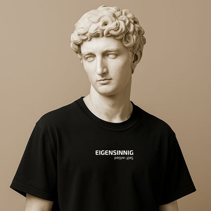 Minimalist unisex t-shirt with “Eigensinnig” printed in bold font on the statue. Cotton fabric, black or white. Word for independent thinking.