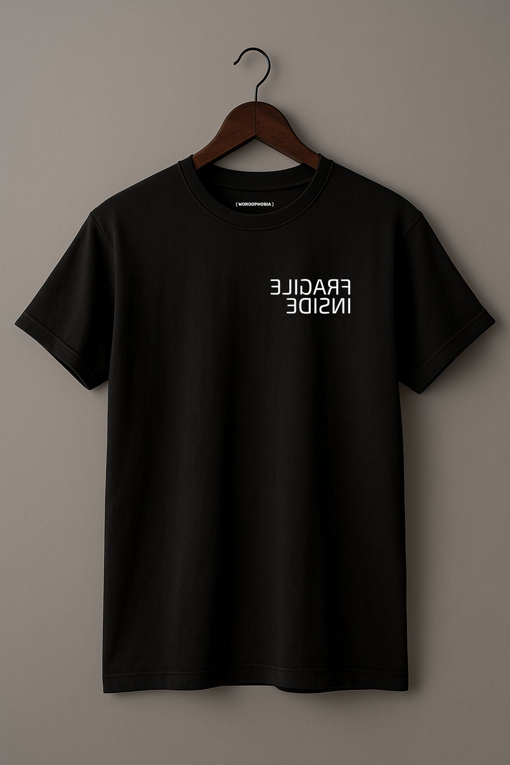 Mockup of minimalist folded t-shirt with phrase “Fragile Inside” in black cotton
