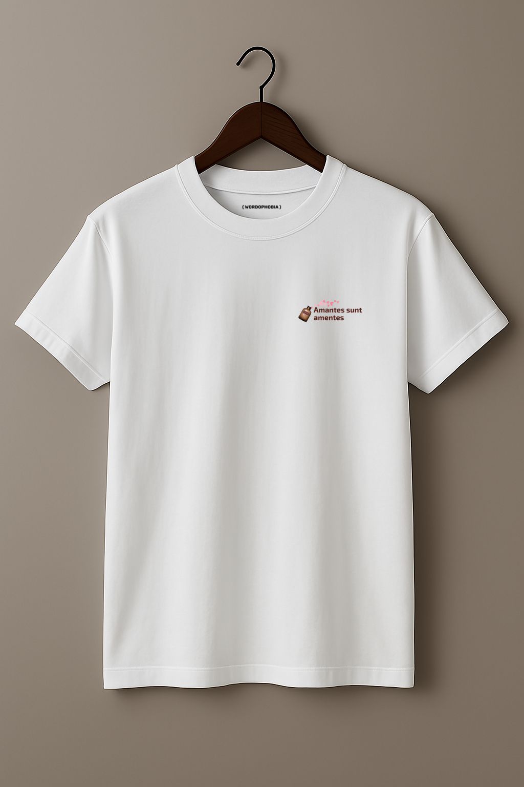 White t-shirt with a small design of a Latin phrase "Amantes sunt amentes"  and small graphic of hearts on a wooden hanger against a plain background
