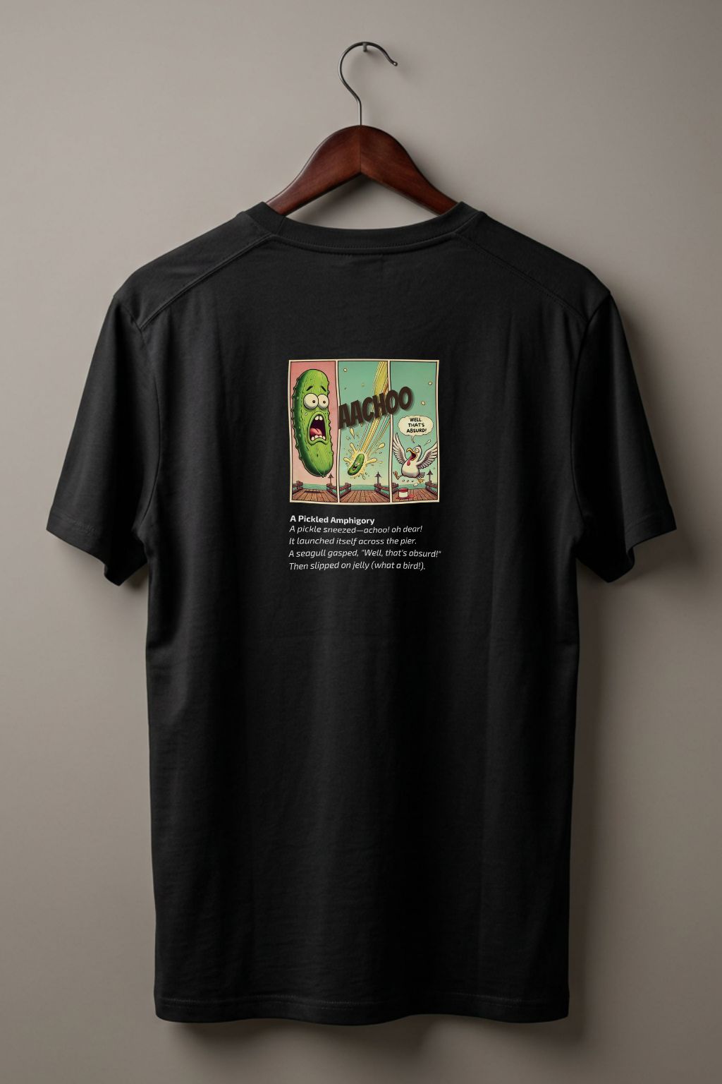 Black t-shirt (back side)  with a graphic comic design of a pickle and a poem below on a hanger against a plain wall