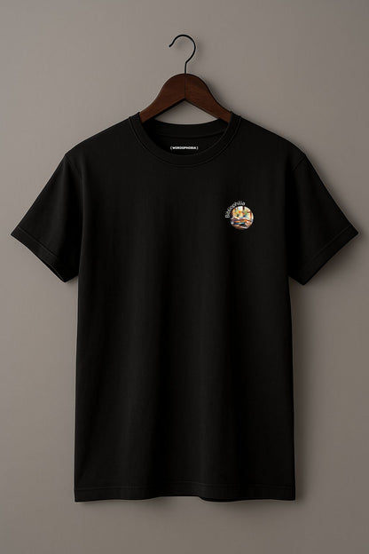 Black t-shirt with a graphic design of a watercolor painting with pile of books and flowers near the window and text "Bibliophilia" on a wooden hanger against a plain background