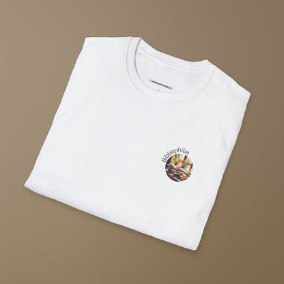Folded white T-shirt with a graphic design of a watercolor painting with pile of books and flowers near the window and text "Bibliophilia"  on a brown background