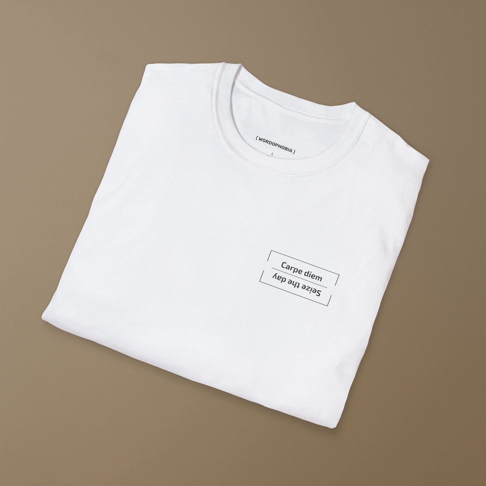 Folded white t-shirt with the Latin phrase “Carpe diem,” meaning “Seize the day,” printed in clean modern typography on a beige background 