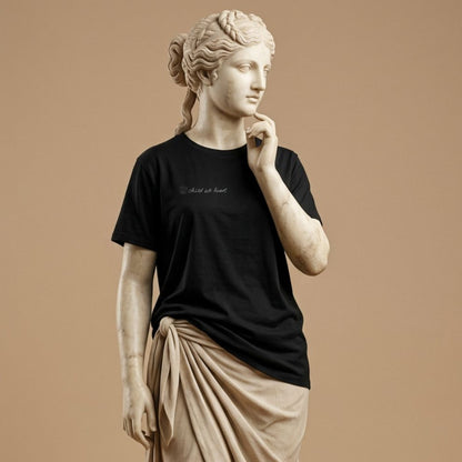 Statue wearing a black t-shirt with graphic design of hand drawn kids picture of the funny face and the hand written text "child at heart" on a beige background