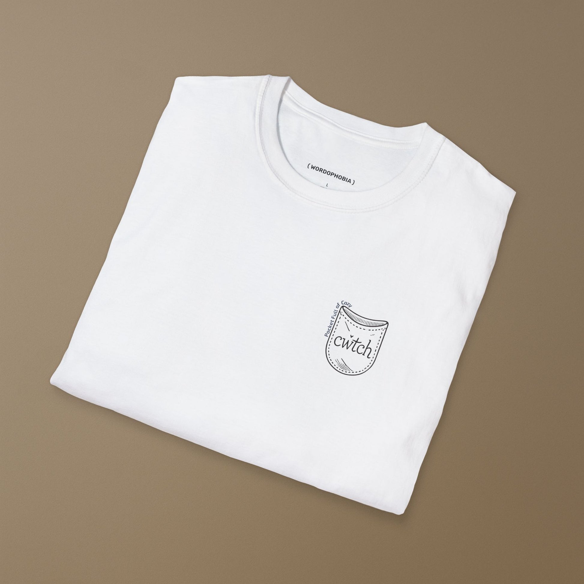 Folded white t-shirt with a small graphic design of a tiny pocket with 'cwtch' word and text "Pocket Full of Cozy" on a beige background