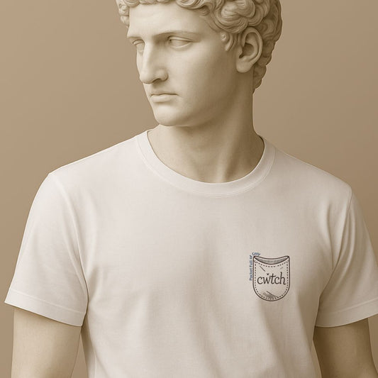 Statue wearing a white t-shirt with a small graphic design of a tiny pocket with 'cwtch' word and text "Pocket Full of Cozy" on a beige background