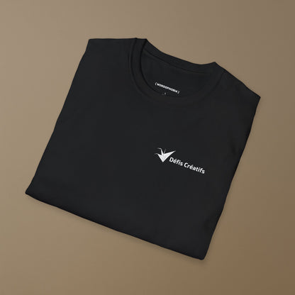 Folded black t-shirt with a stylized crane and the text 'Défis Créatifs' text on a brown background
