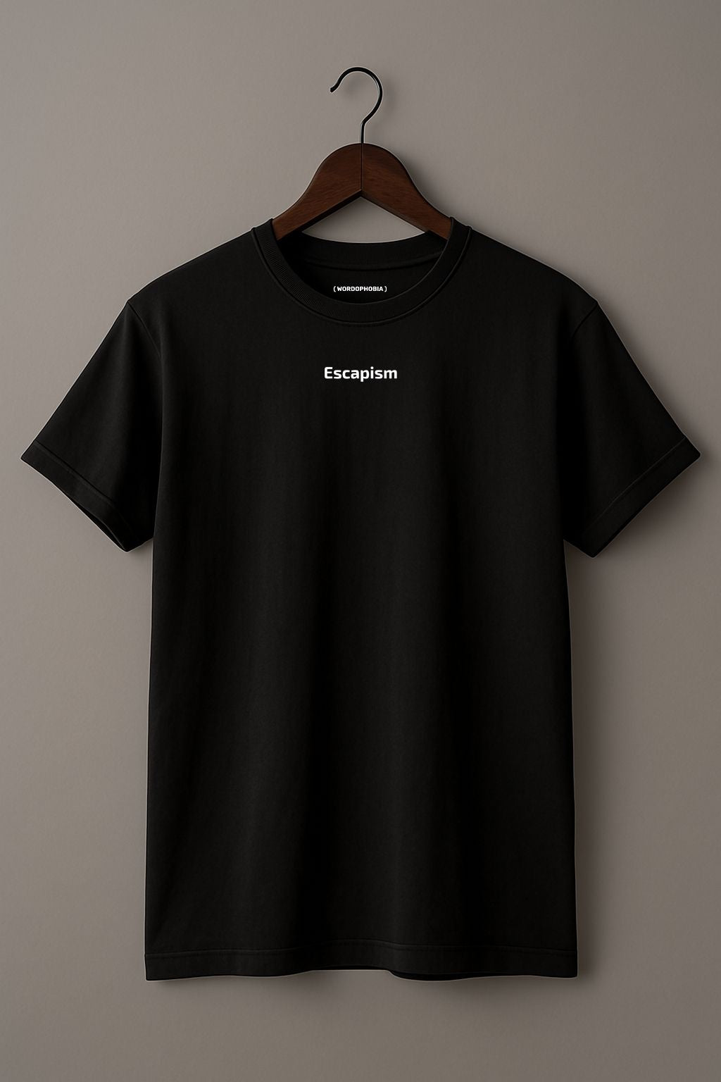 Black t-shirt with 'Escapism' text on a wooden hanger against a beige background