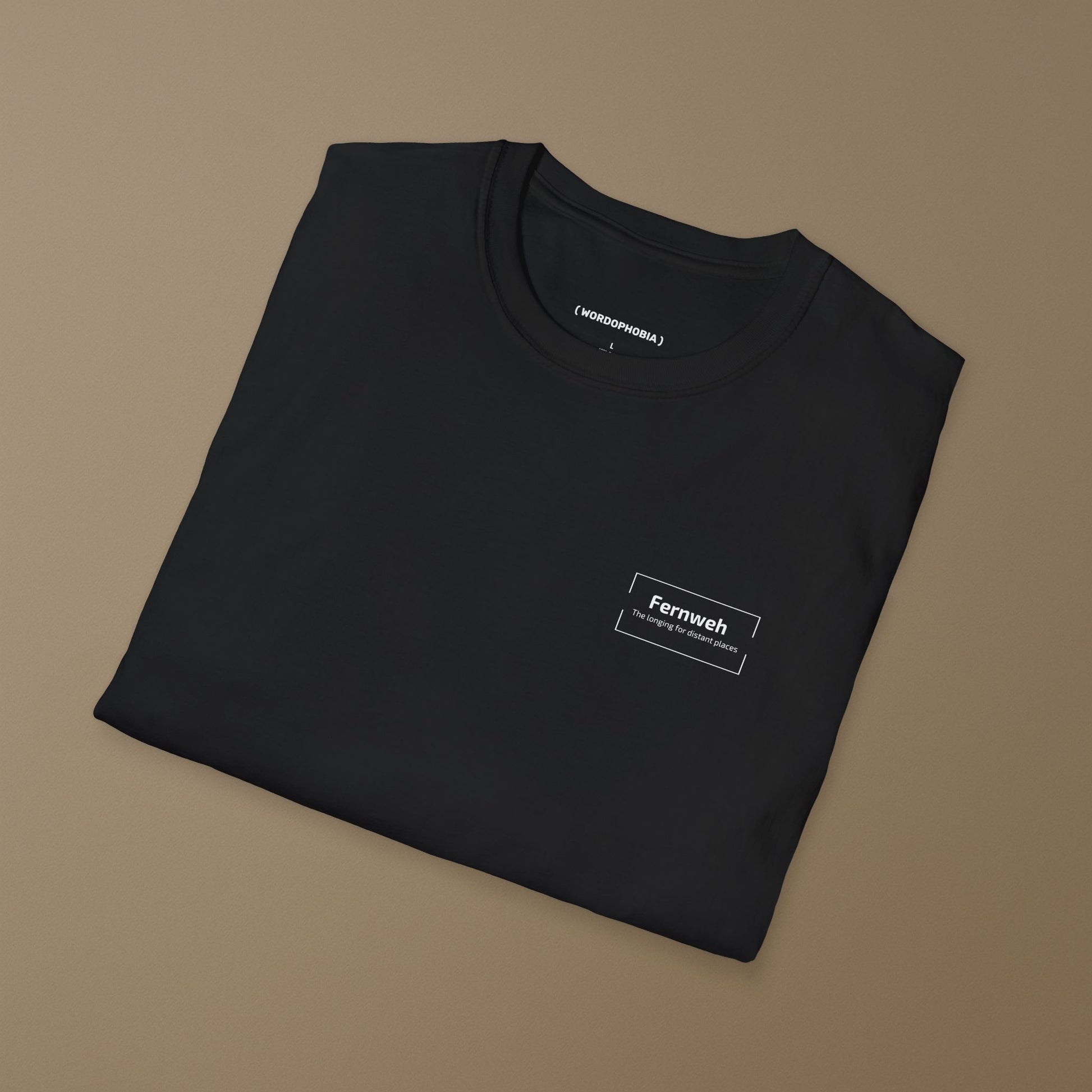 Folded black t-shirt with a small design of  the word 'Fernweh' and tagline 'The longing for distant places' on a beige background