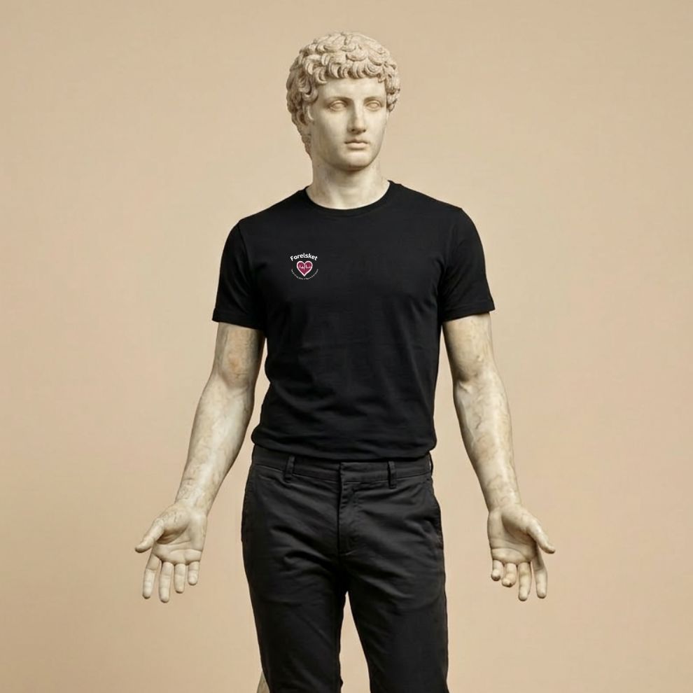 Statue wearing a black t-shirt with a small design of a heart with a beat and texts  "Forelsket" and "The thrilling glow of love's first bloom" on a beige background