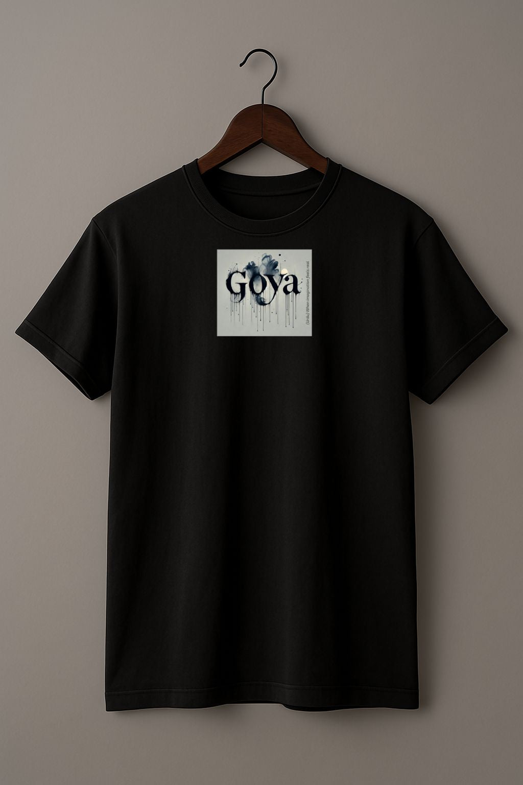 Black t-shirt with a graphic design "Goya" on a hanger against a plain background