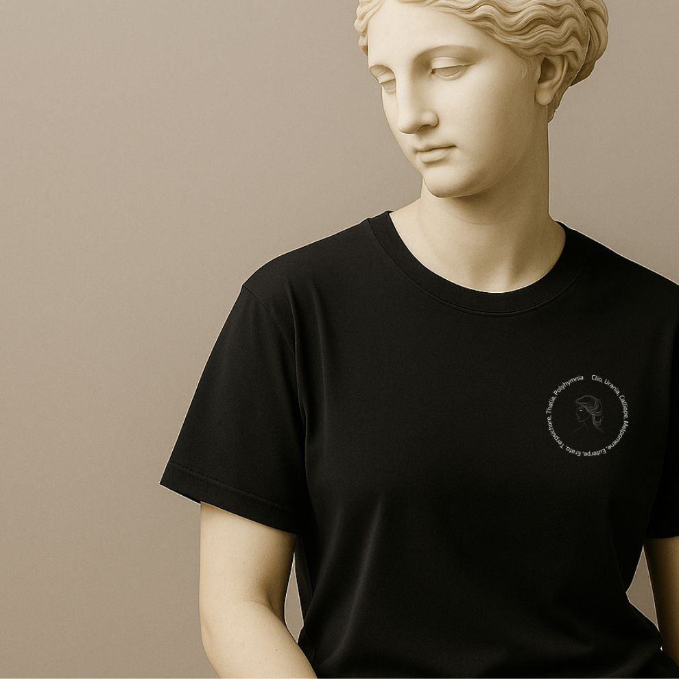 Statue wearing a black t-shirt with a graphic of a line drawing of a classical woman's profile with Greek goddess names around her head on a white background on a beige background