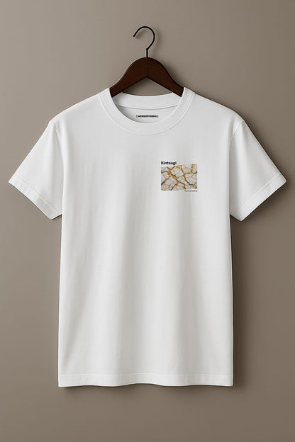 White t-shirt with a small graphic of Kintsugi art with gold repair on a cracked white surface, text 'Kintsugi The art of healing' above on a hanger against a beige background