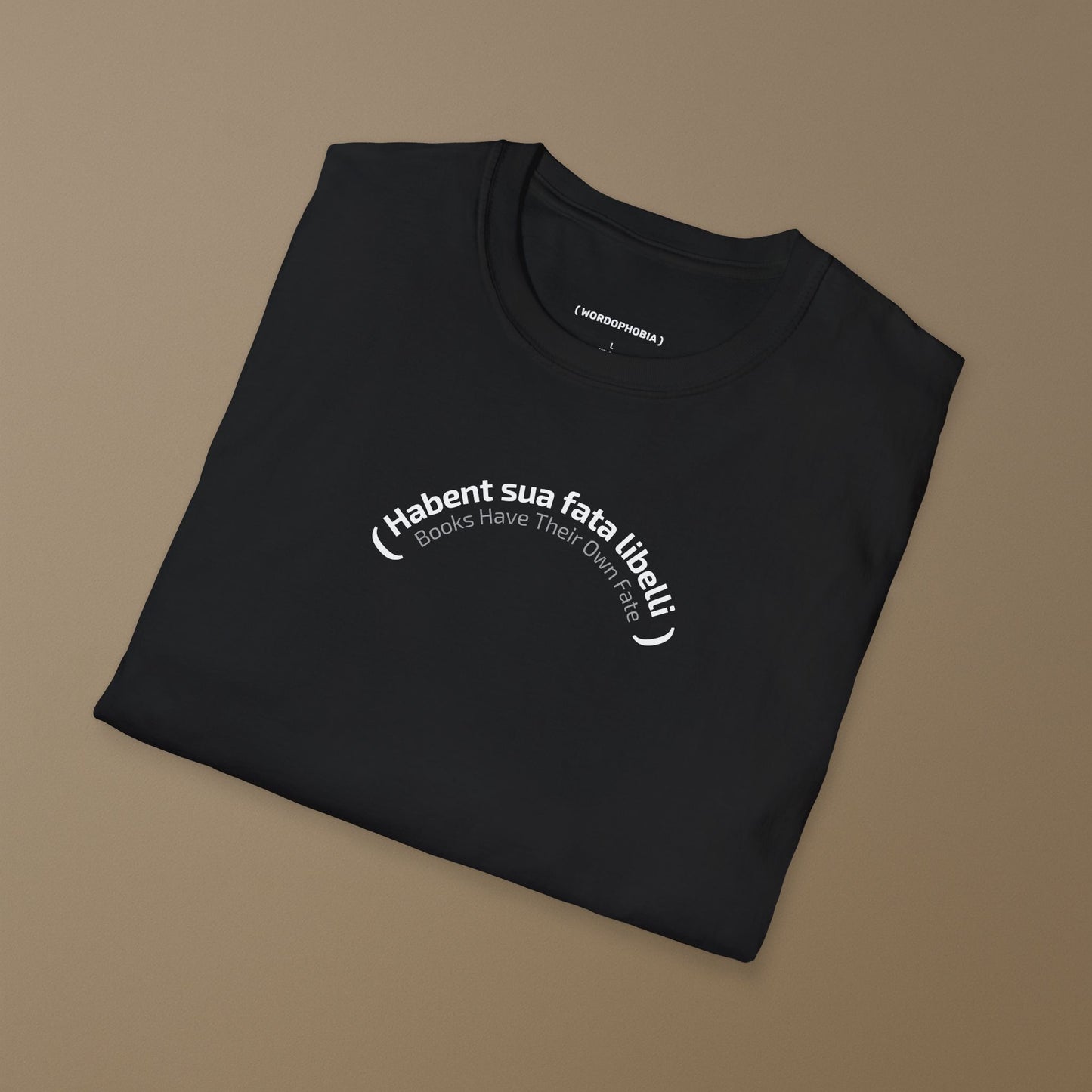 Folded black t-shirt with Latin phrase 'Habent sua fata libelli' and its translation "Books Have Their Own Fate"  on a brown background