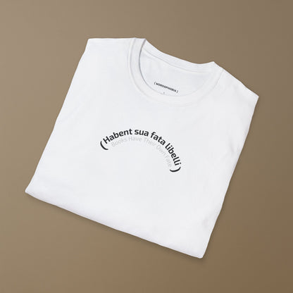 Folded white t-shirt with Latin phrase 'Habent sua fata libelli' and its translation "Books Have Their Own Fate"  on a brown background
