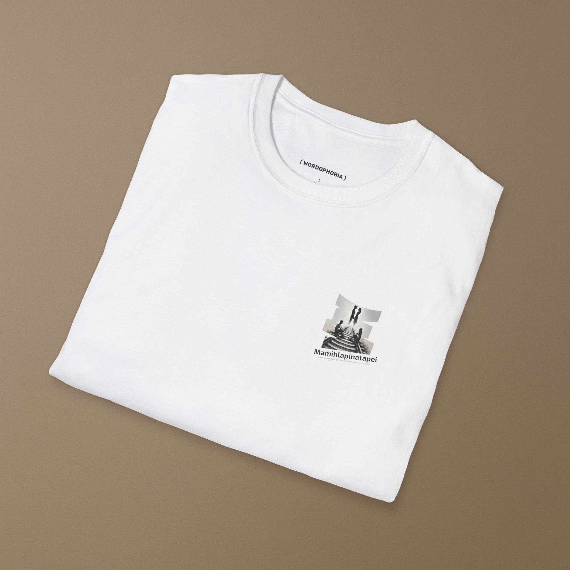 Folded white t-shirt with a graphic of a silhouette artwork of two people on a railway track with text 'Mamihlapinatapei' 