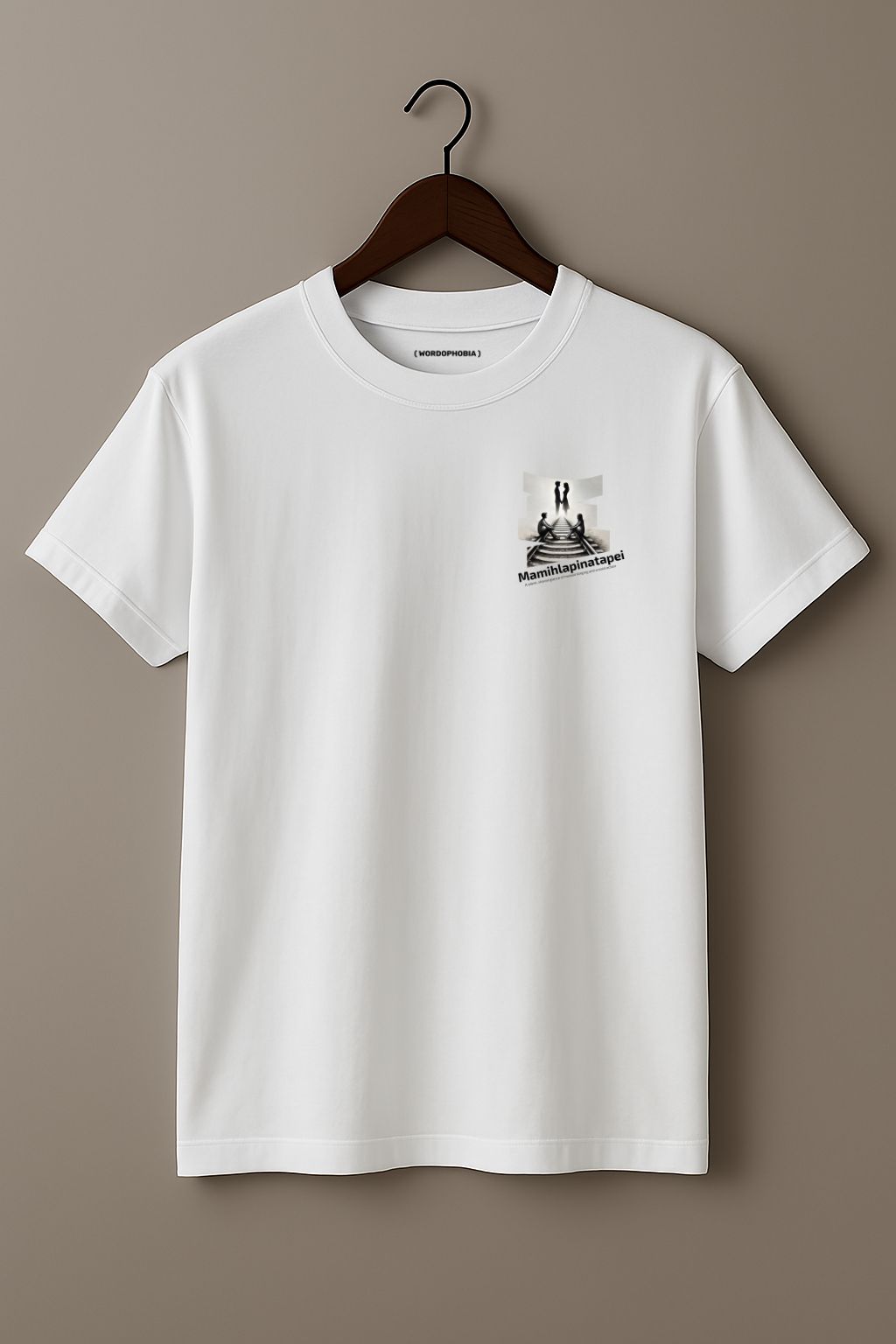 White t-shirt with a graphic of a silhouette artwork of two people on a railway track with text 'Mamihlapinatapei' below on a wooden hanger against a plain background