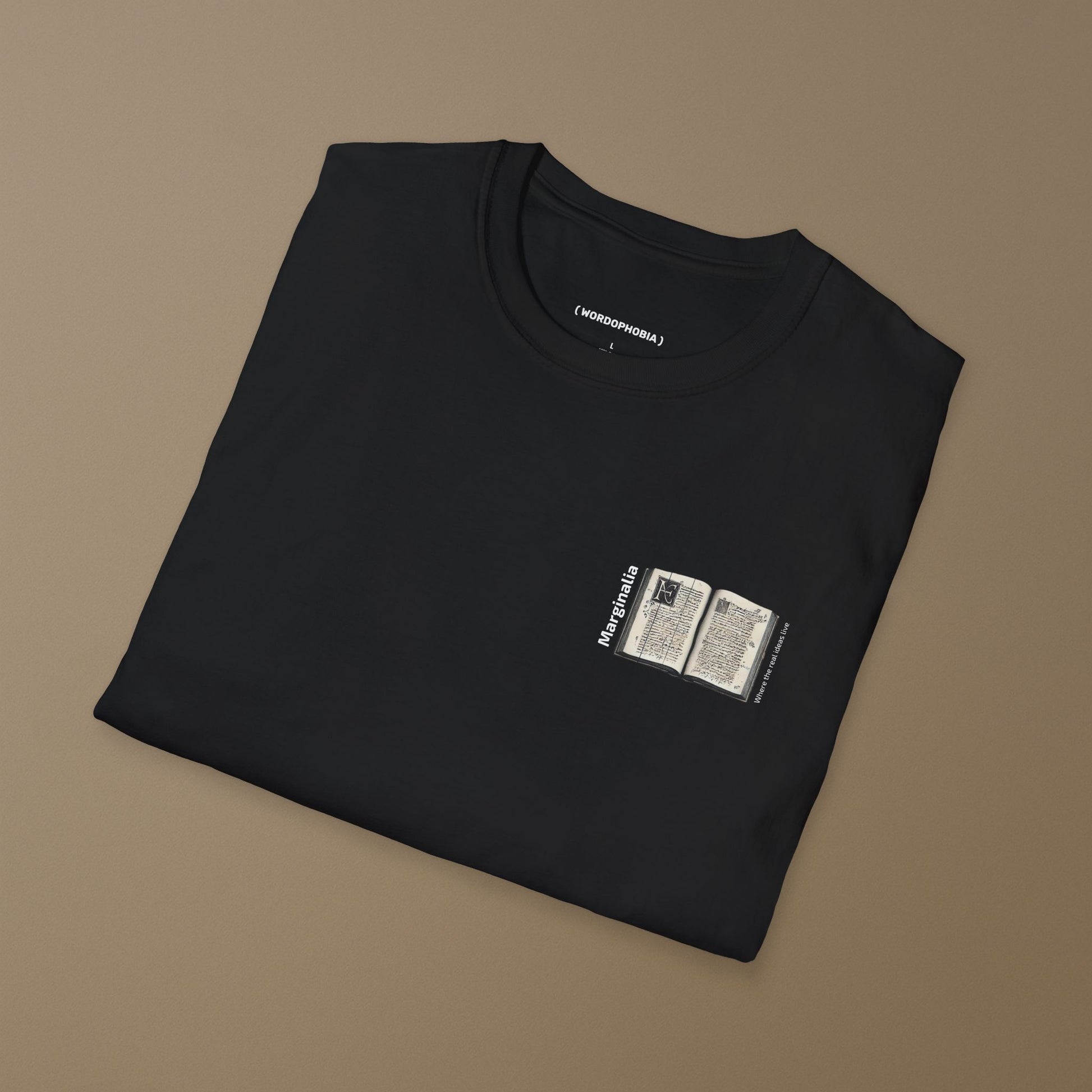 Folded black t-shirt with a small graphic of White t-shirt with a small graphic of open old book with text "Marginalia" and "Where the real ideas live" on a beige background
