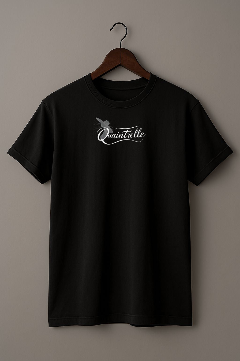 Black t-shirt with a small design of a word Quaintrelle, symbolizing elegant and intentional living, and silhouette of women on a hanger against a beige background
