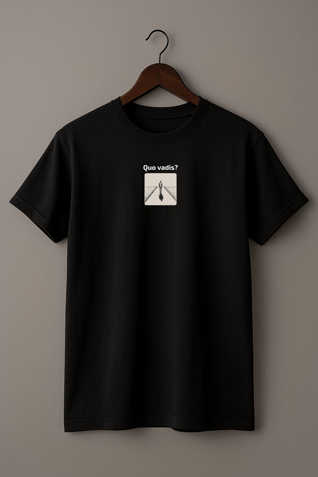 Black t-shirt with an illustration of a person standing on a path with 'Quo vadis?' text above on a hanger against a beige background