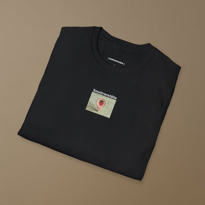 Folded black t-shirt with a graphic design of a map marker with strawberry design and text 'Smultronställe' on a light background on a plain background 