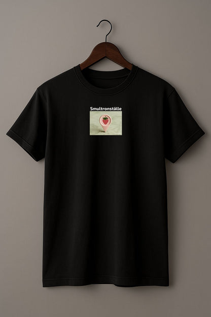 Black t-shirt with a graphic design of a map marker with strawberry design and text 'Smultronställe' on a light background on a hanger against a plain background