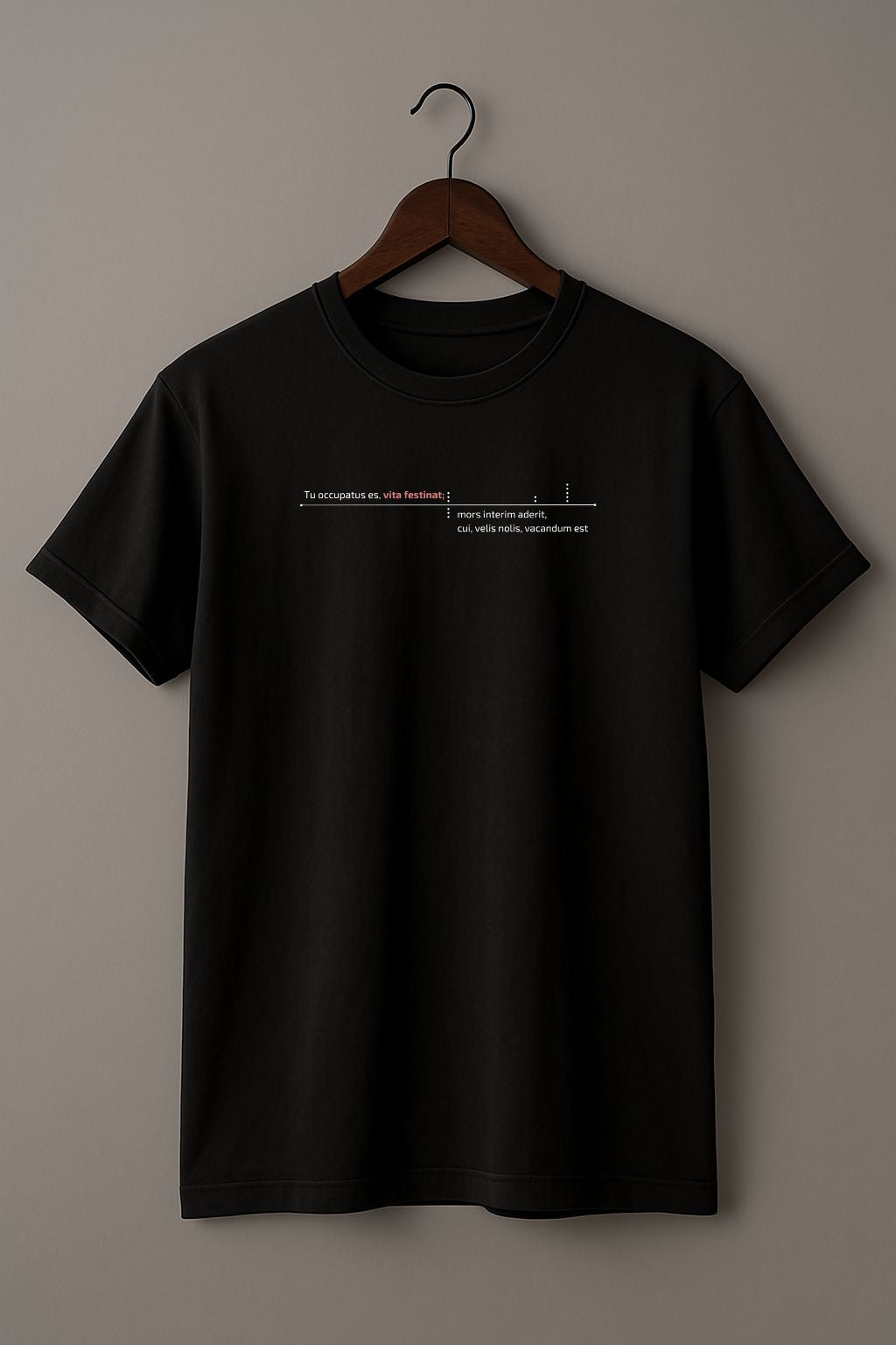 Black t-shirt with latin phrase " Tu occupatus es, vita festinat mors interm aderit" on a wooden hanger against a beige background