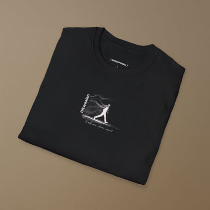 Folded black t-shirt featuring the Dutch word “Uitwaaien,” meaning “fresh air, clear mind,” with a small hand-drawn figure walking into the wind on a beige background