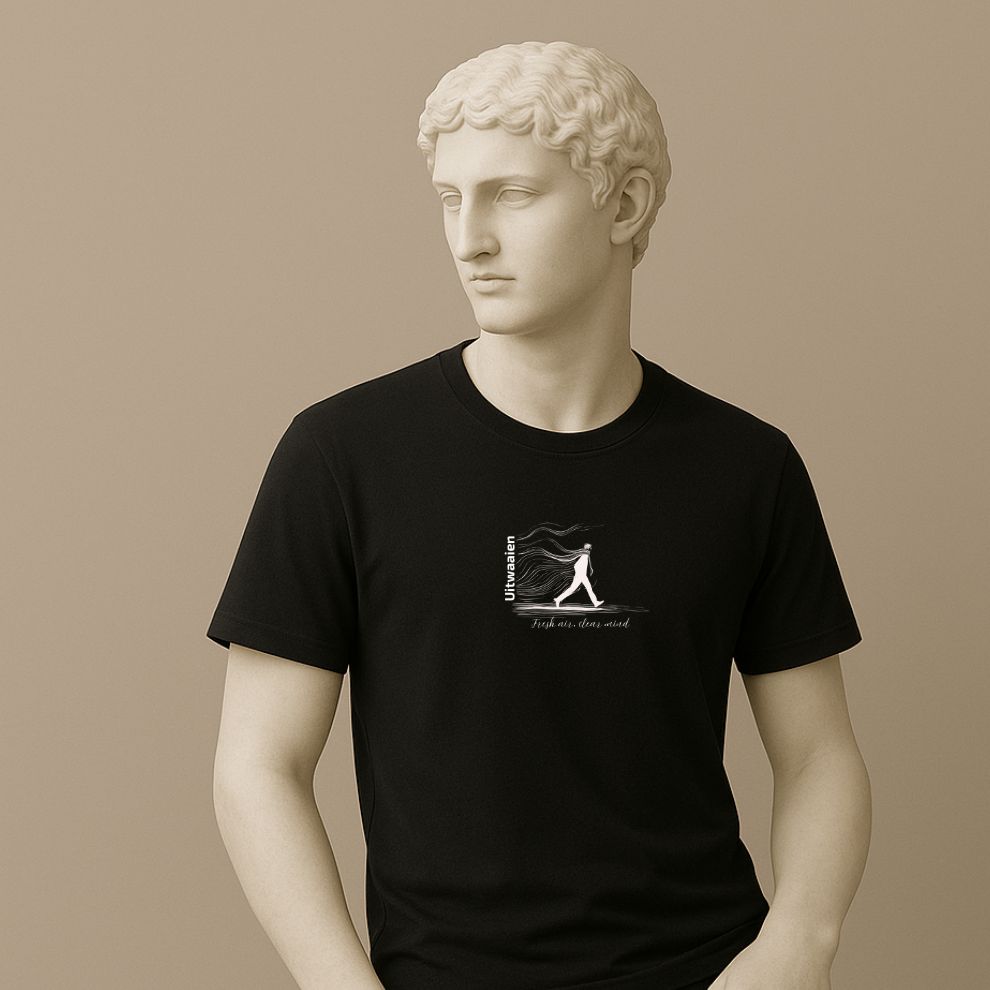 Statue wearing a black t-shirt featuring the Dutch word “Uitwaaien,” meaning “fresh air, clear mind,” with a small hand-drawn figure walking into the wind.