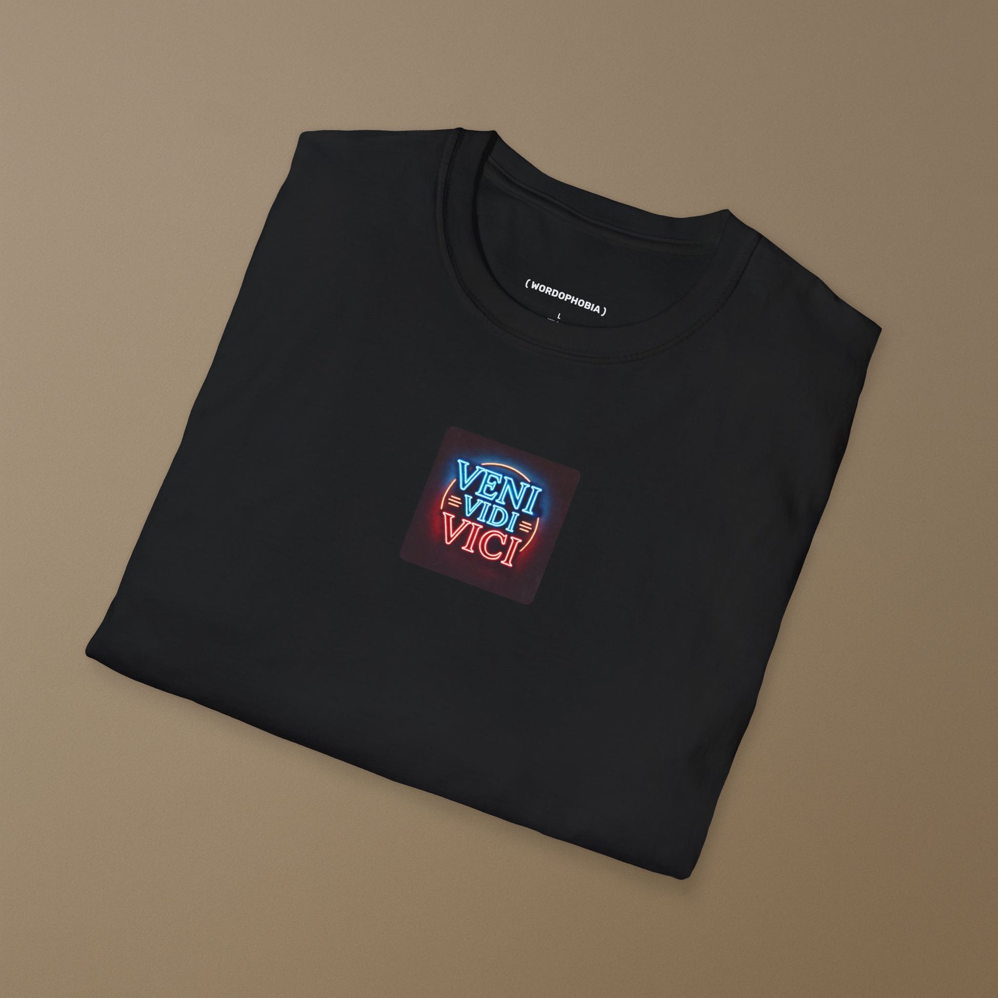 Folded black t-shirt with a colorful patch with the Latin phrase "Veni, Vidi, Vici" on a dark background