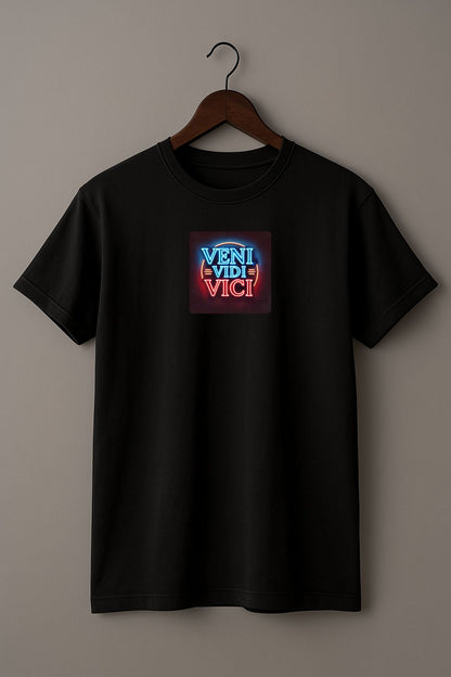 Black t-shirt with a colorful graphic with the Latin phrase "Veni, Vidi, Vici" on a hanger against a beige background 
