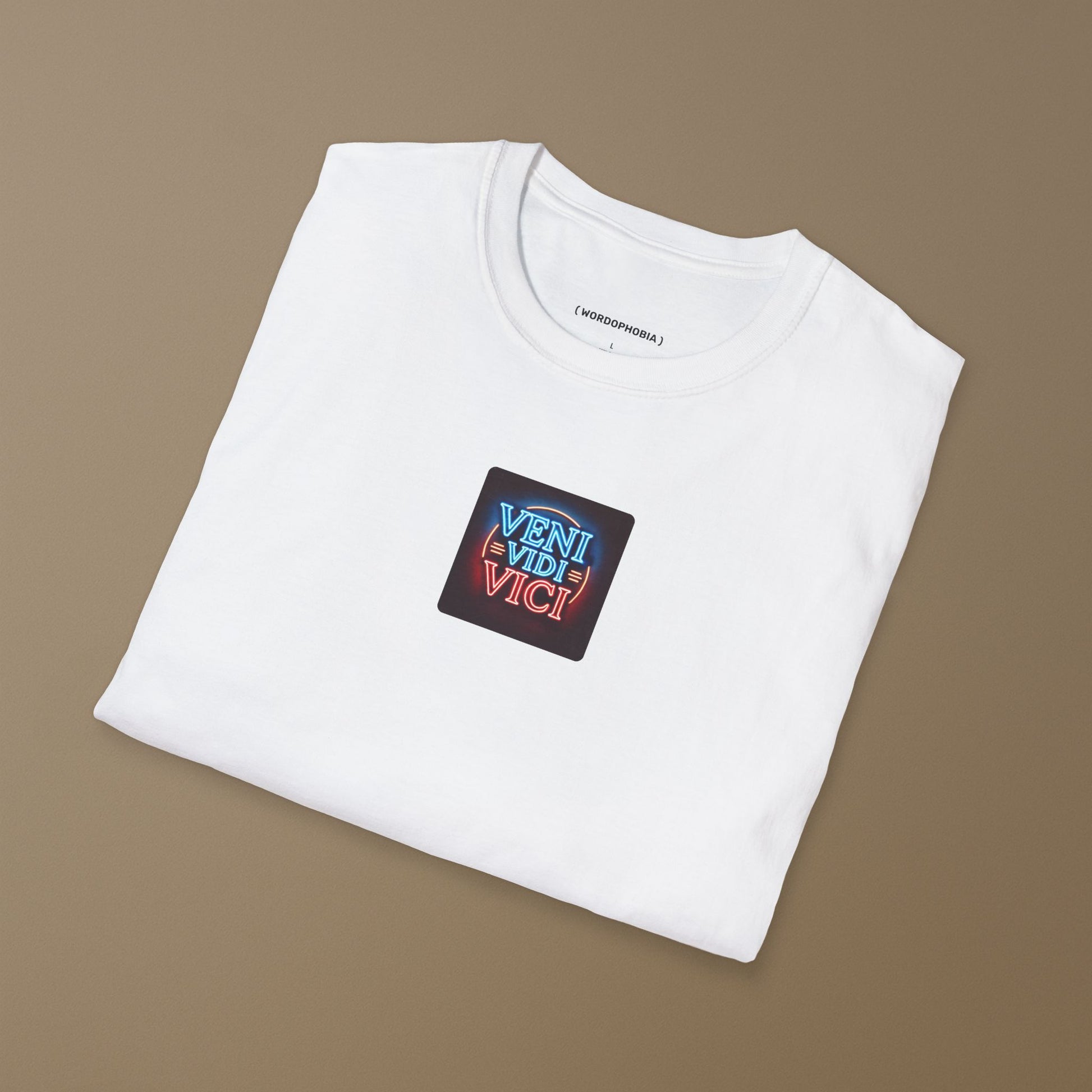 Folded white t-shirt with a colorful patch with the Latin phrase "Veni, Vidi, Vici" on a dark background