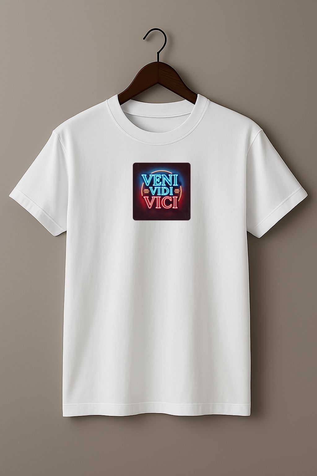White t-shirt with a colorful graphic with the Latin phrase "Veni, Vidi, Vici" on a hanger against a beige background 