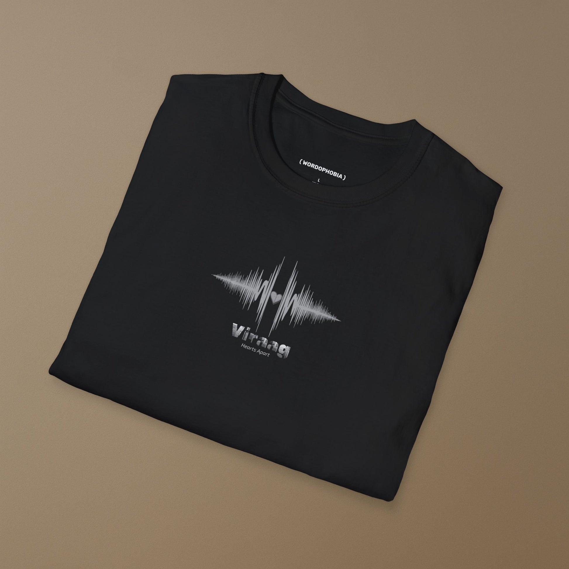 Folded black t-shirt with a white sound wave design with a heart symbol and 'Viraag' (Hearts Apart) text on a beige background 