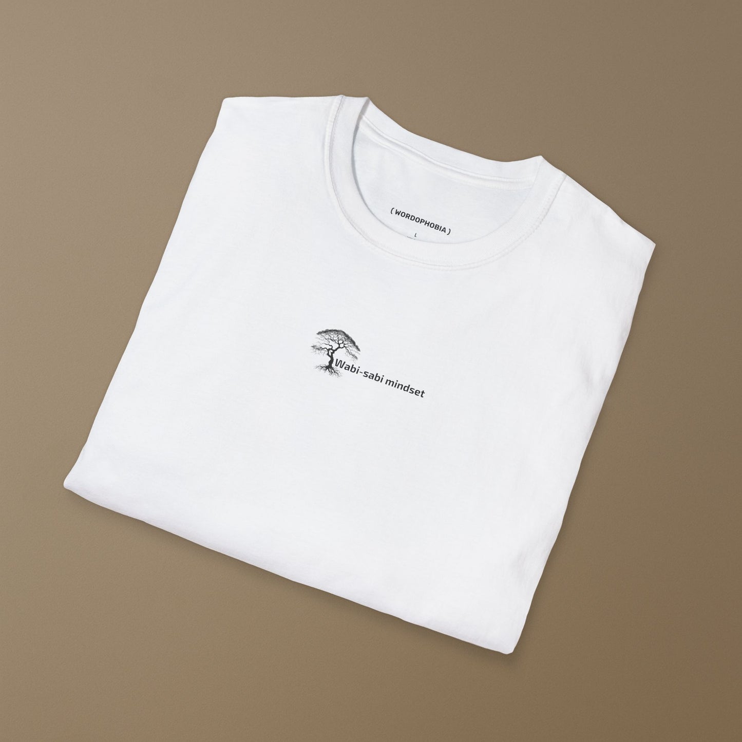 Folded white t-shirt with a small white design of an icon with 'Wabi-sabi mindset' text on a plain background
