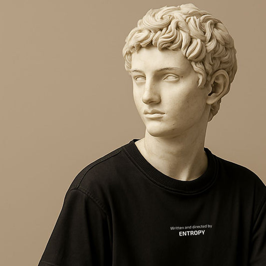 Minimalist t-shirt with phrase “Written and Directed by Entropy” in soft black cotton on the roman statue. Clean typography, witty design about chaos and irony.