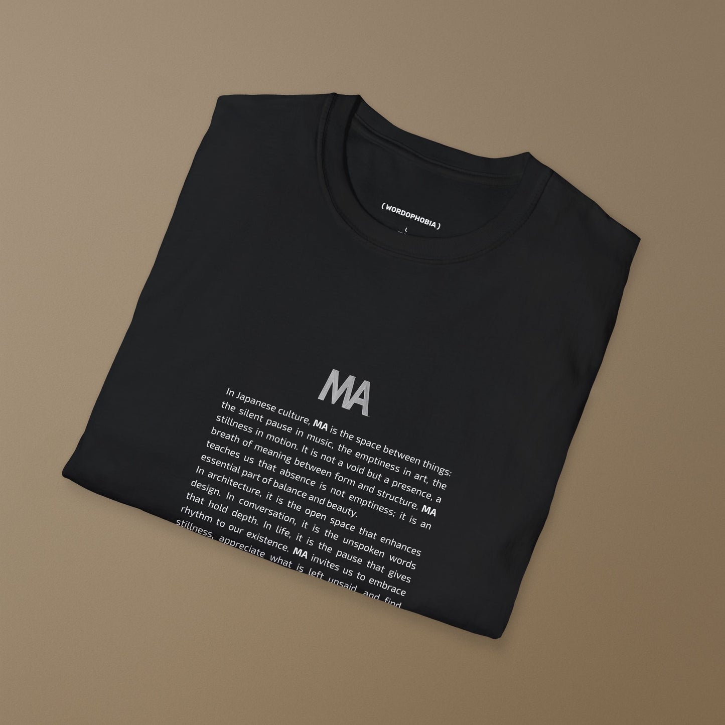 Folded black t-shirt with white text Ma and its concept on a beige background