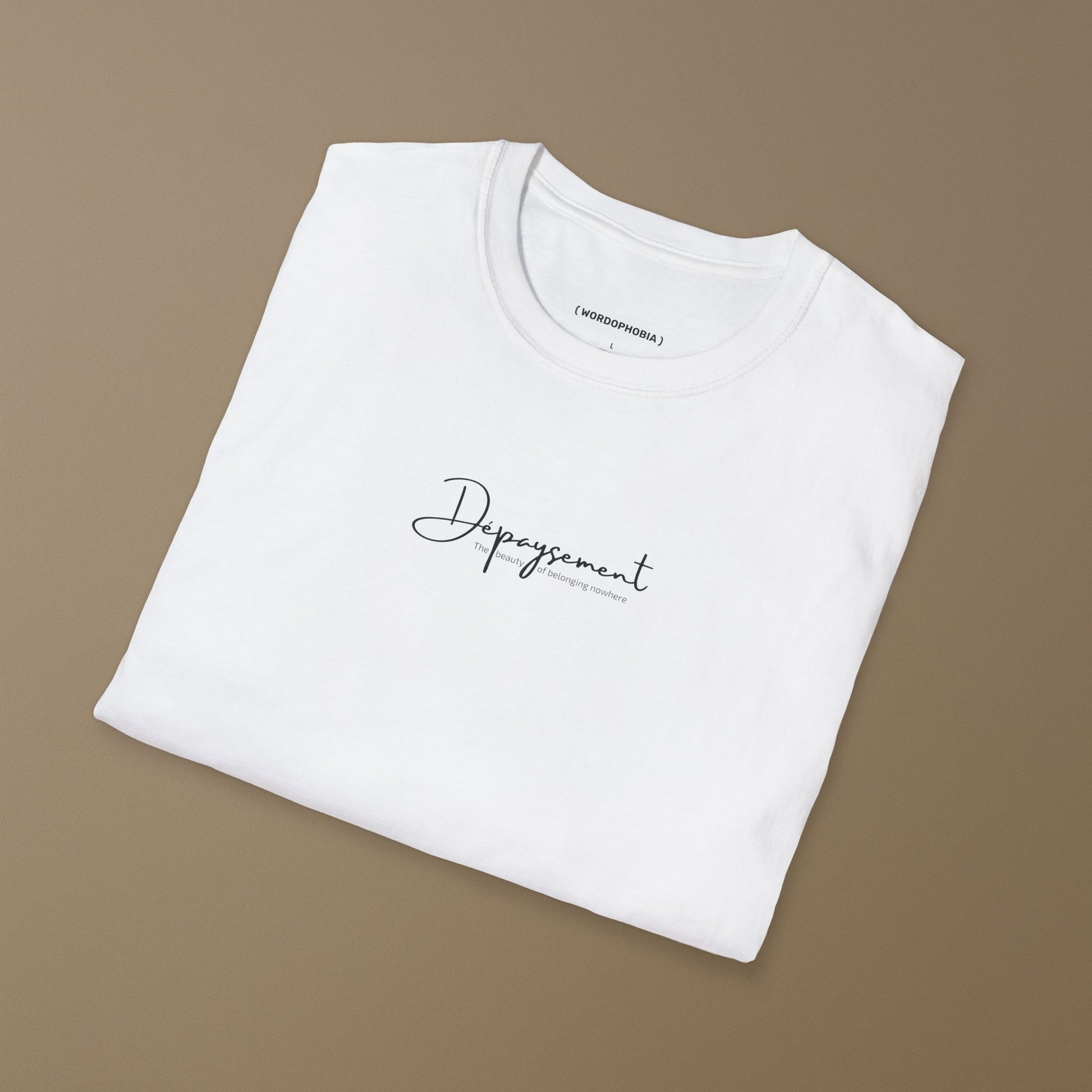 Folded white t-shirt with with the French word Dépaysement printed in elegant typography on a brown background