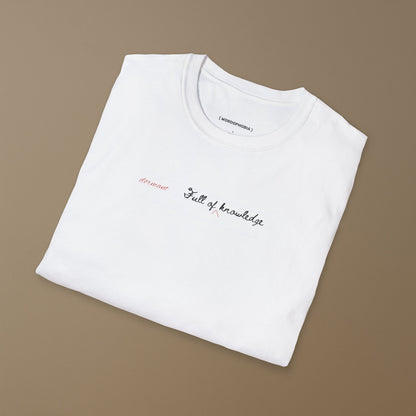 Folded white t-shirt with a white notebook page with 'dormant'  and 'Full of knowledge' on a hanger against a beige background 