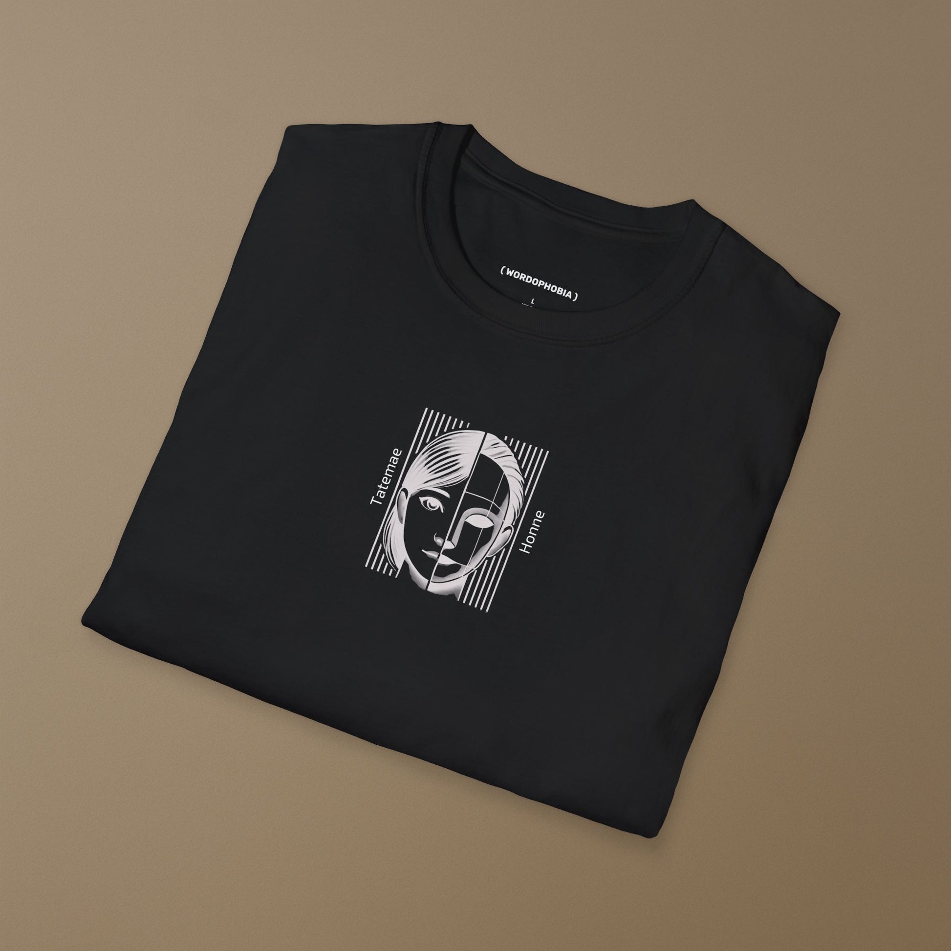 Folded black t-shirt with a graphic design of a face with 'Tatemae' and 'Honne' text on a brown background
